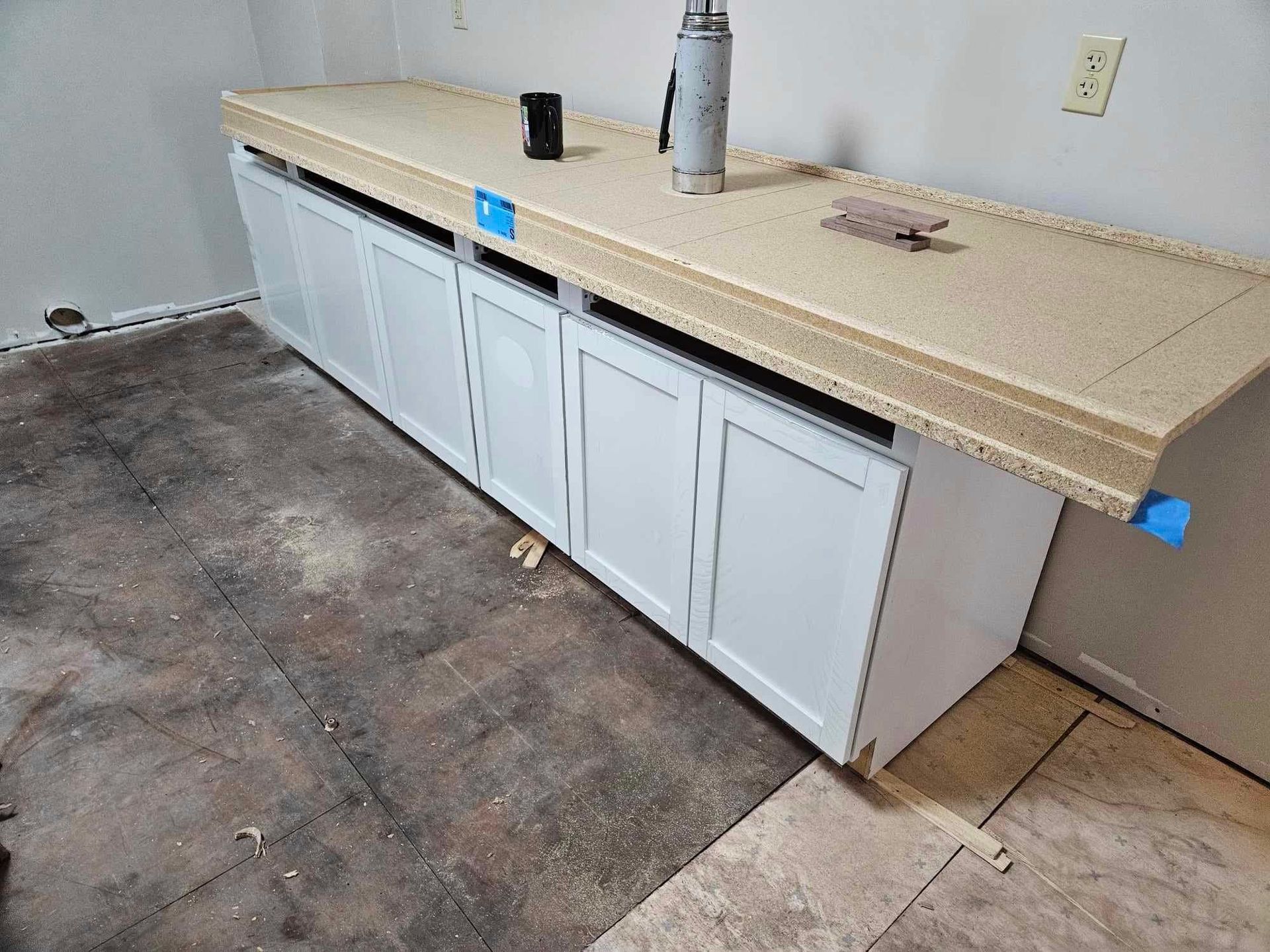 A kitchen counter with white cabinets and a granite counter top.