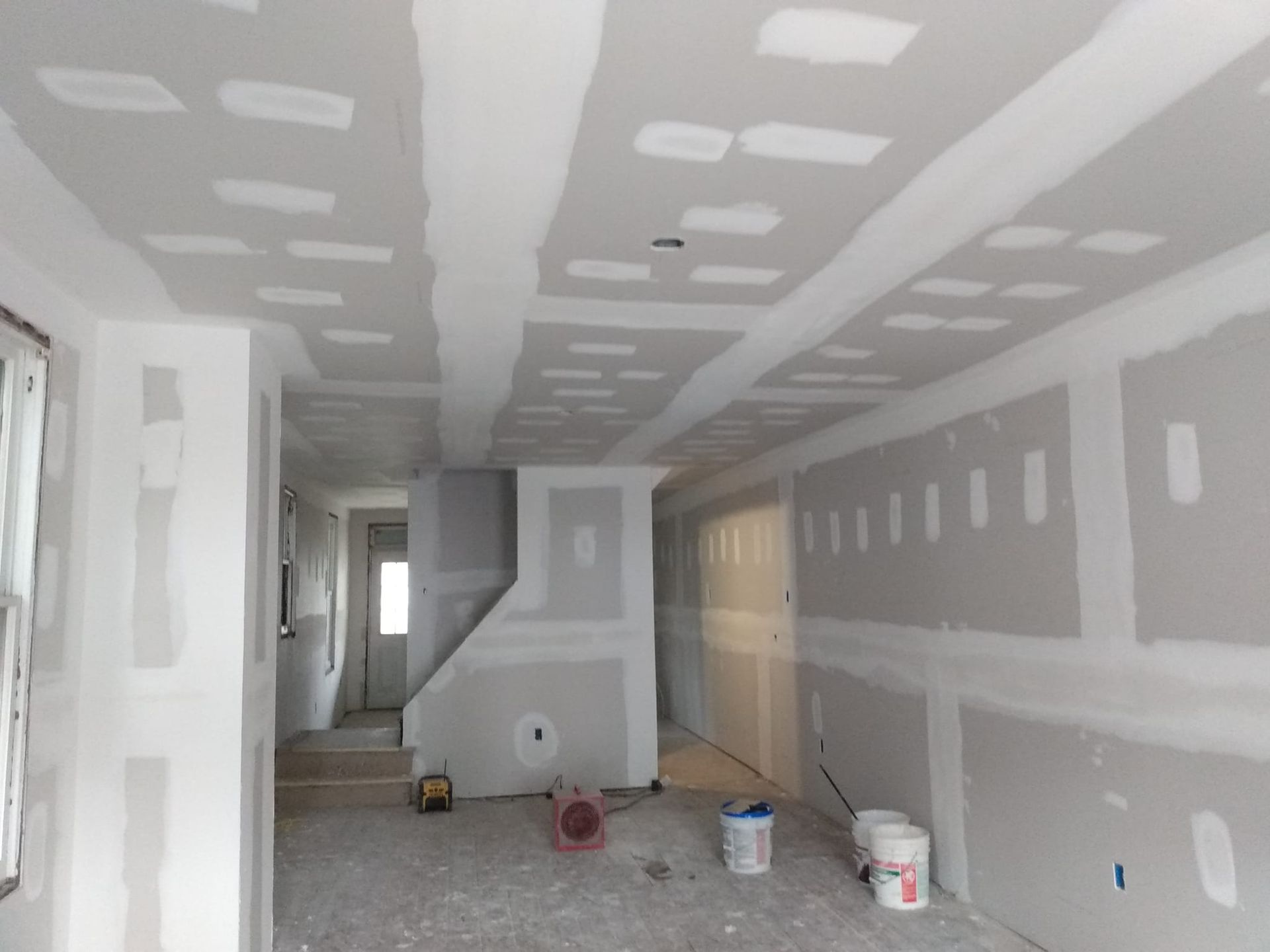 A room that is being remodeled with drywall on the walls and ceiling.