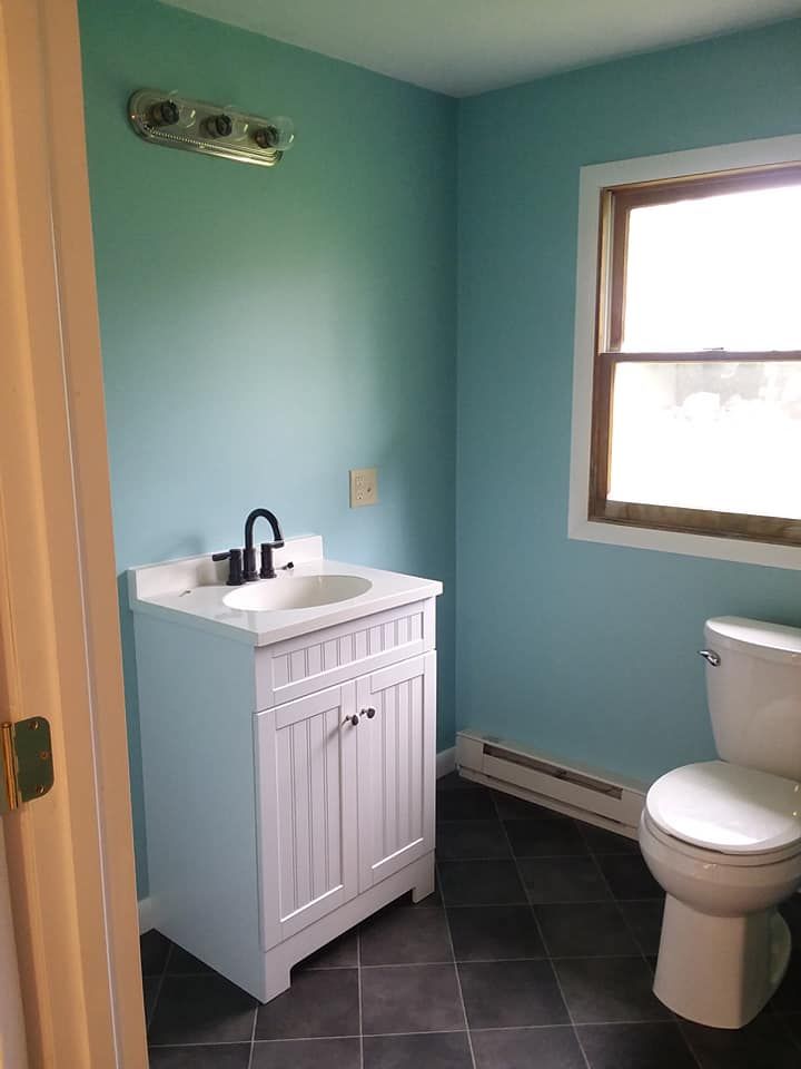 A bathroom with a sink , toilet and window.
