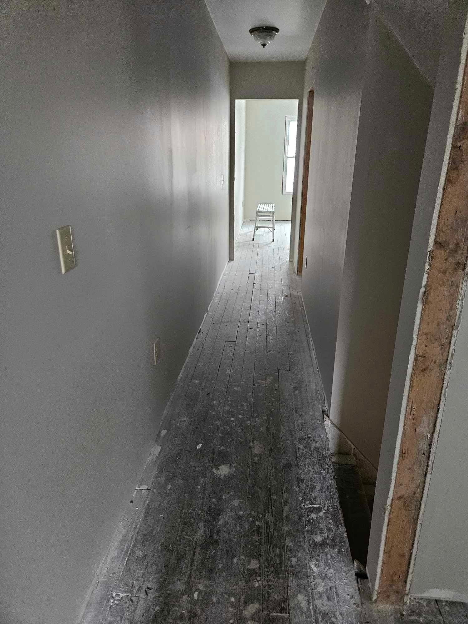 A long hallway with a wooden floor in a house under construction.