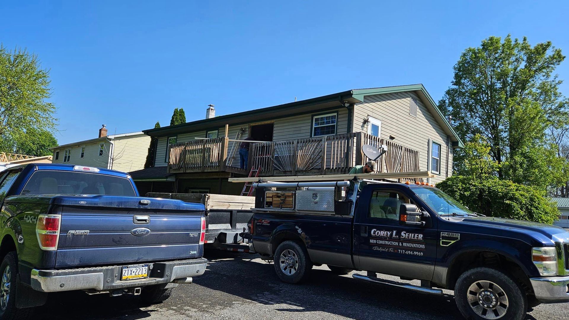 Two trucks are parked in front of a house.