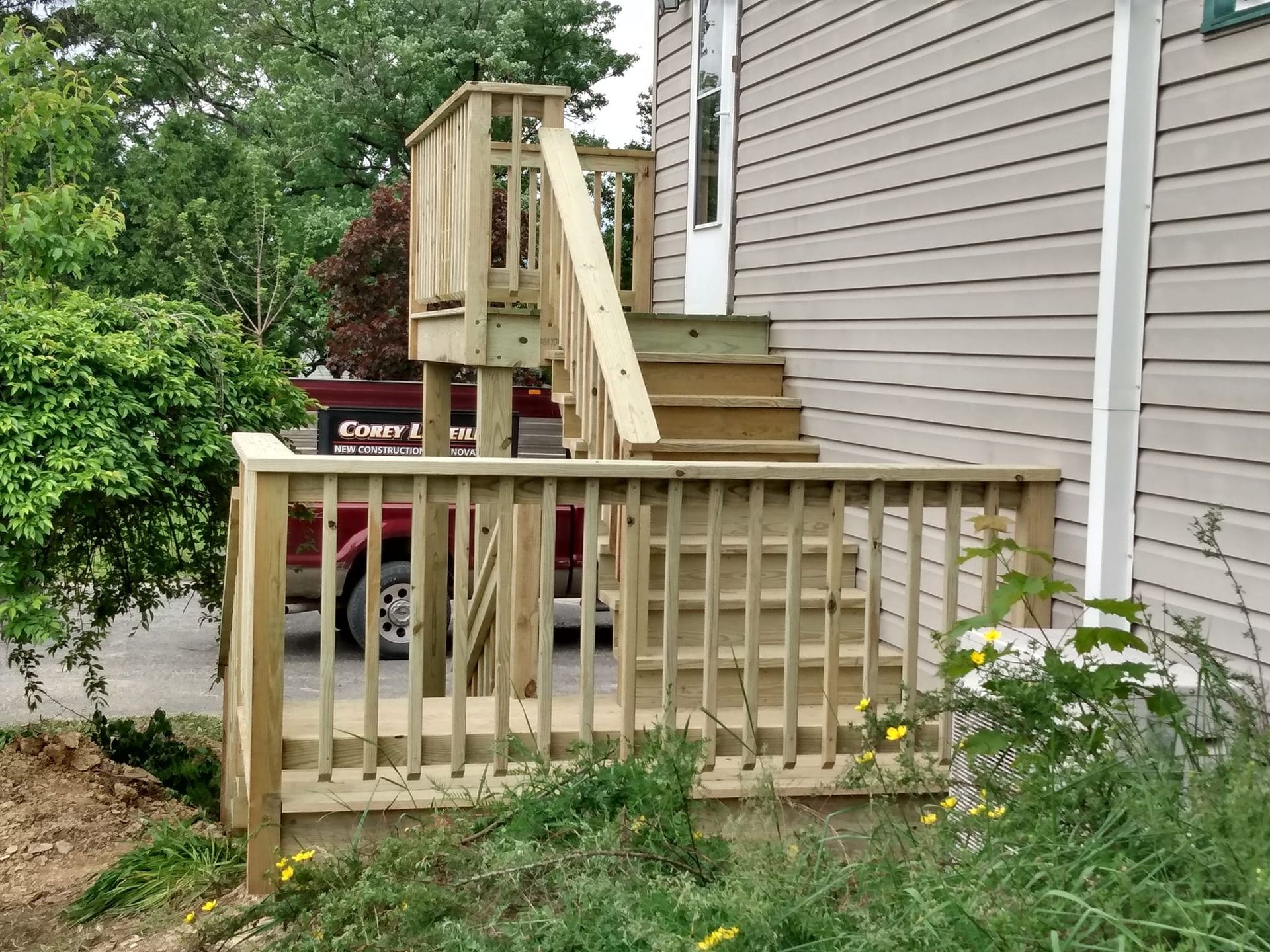 A wooden deck with stairs leading up to the front of a house