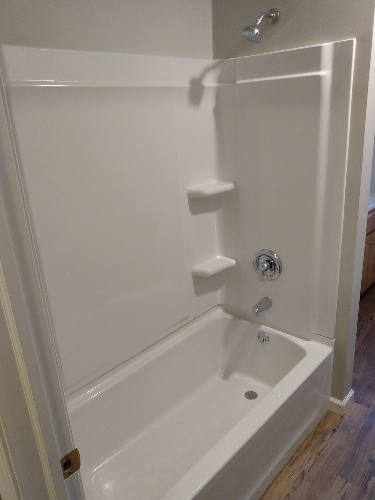 A white bathtub with a shower stall in a bathroom.