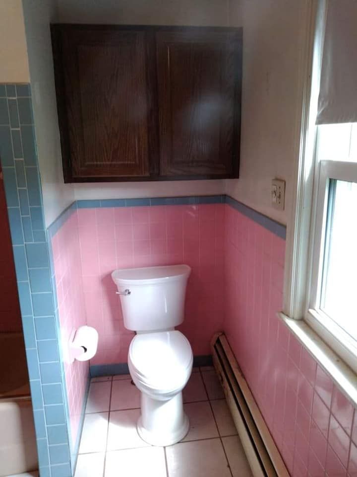 A bathroom with pink tiles and a toilet.