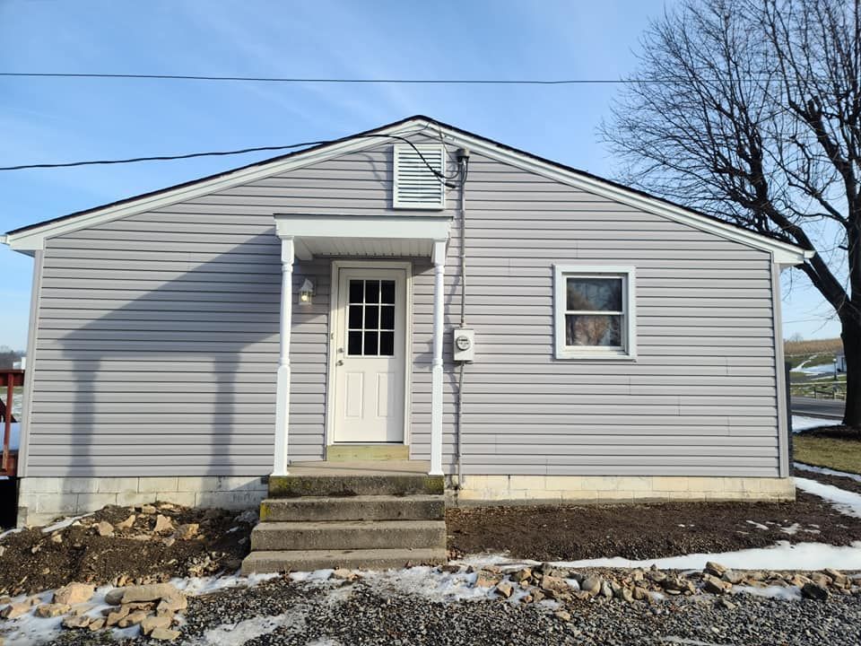A small gray house with a white door and stairs in front of it.