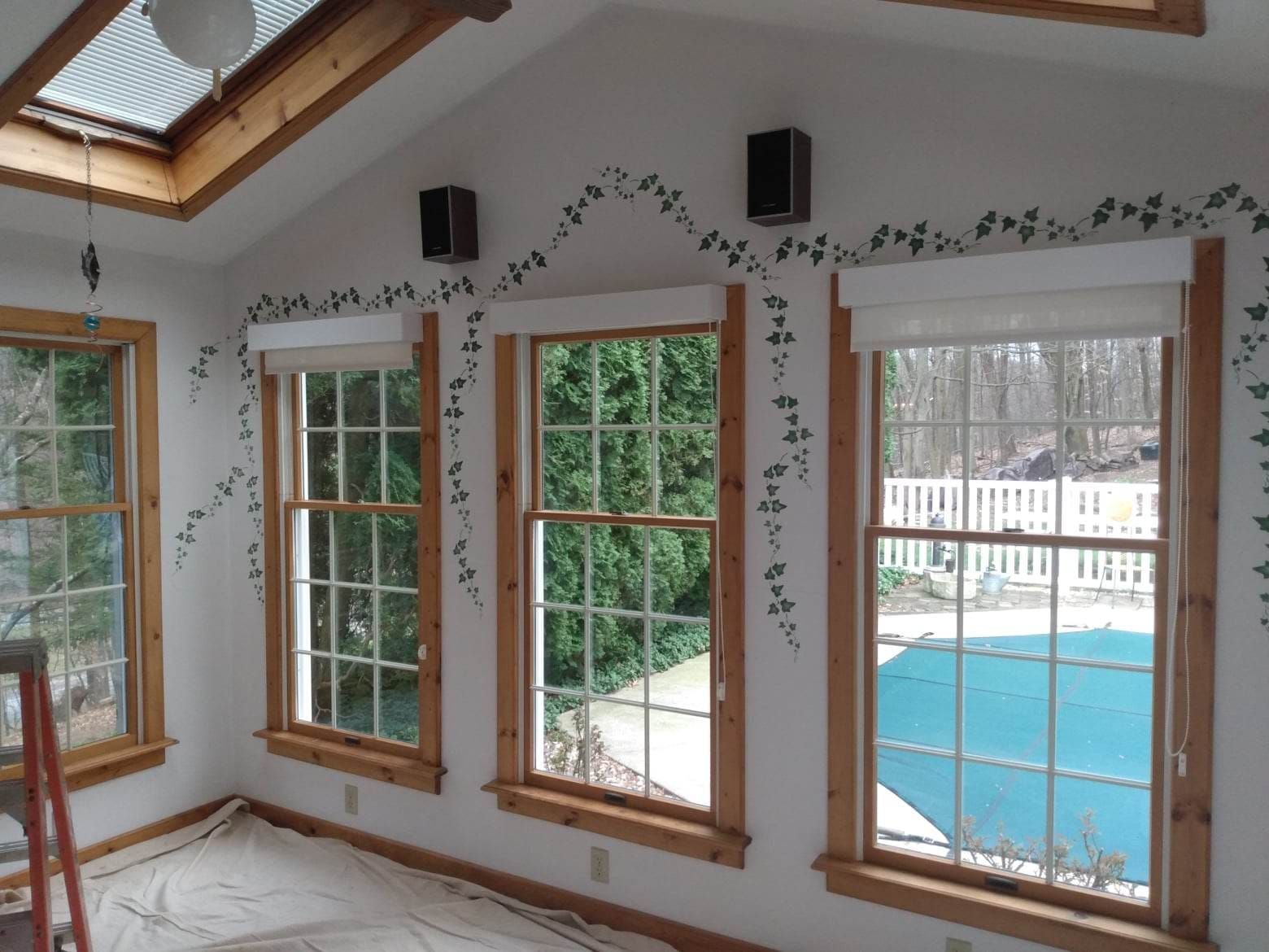 A room with a lot of windows and a pool in the background