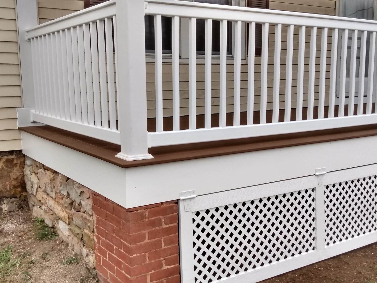 A white porch with a brick wall and a white railing
