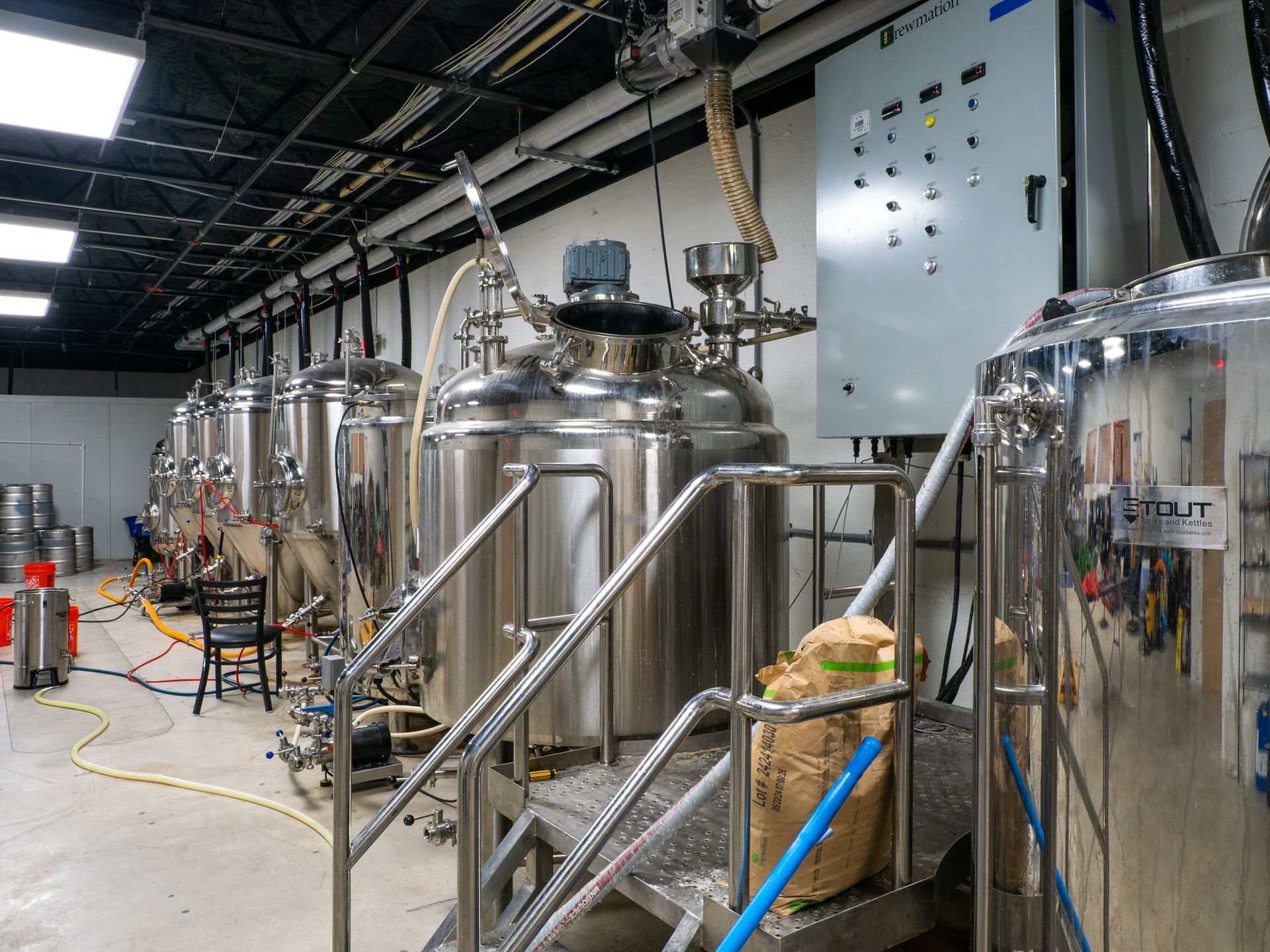 Stainless steel tanks and a control panel in an industrial brewery facility.