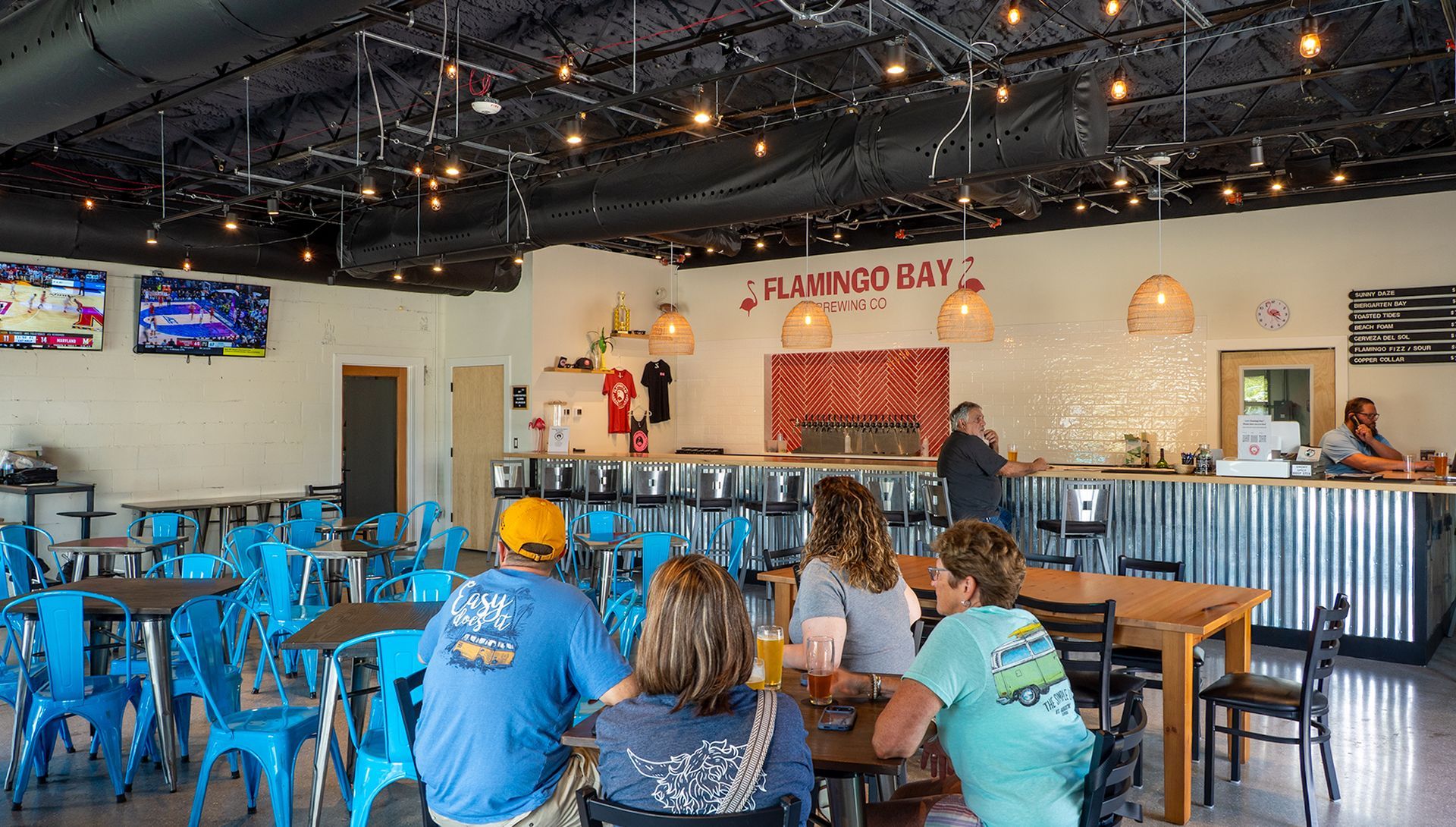 Electrician in yellow hard hat and gloves holding a lit lightbulb.