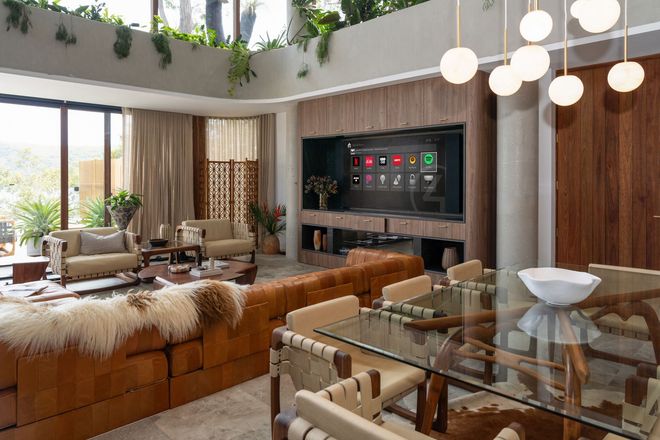 Living room with large TV, leather sofa, dining table, and hanging globe lights
