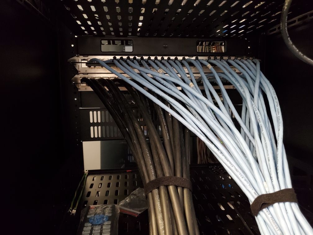 Inside a server rack: network switch with many blue and gray network cables bundled together.
