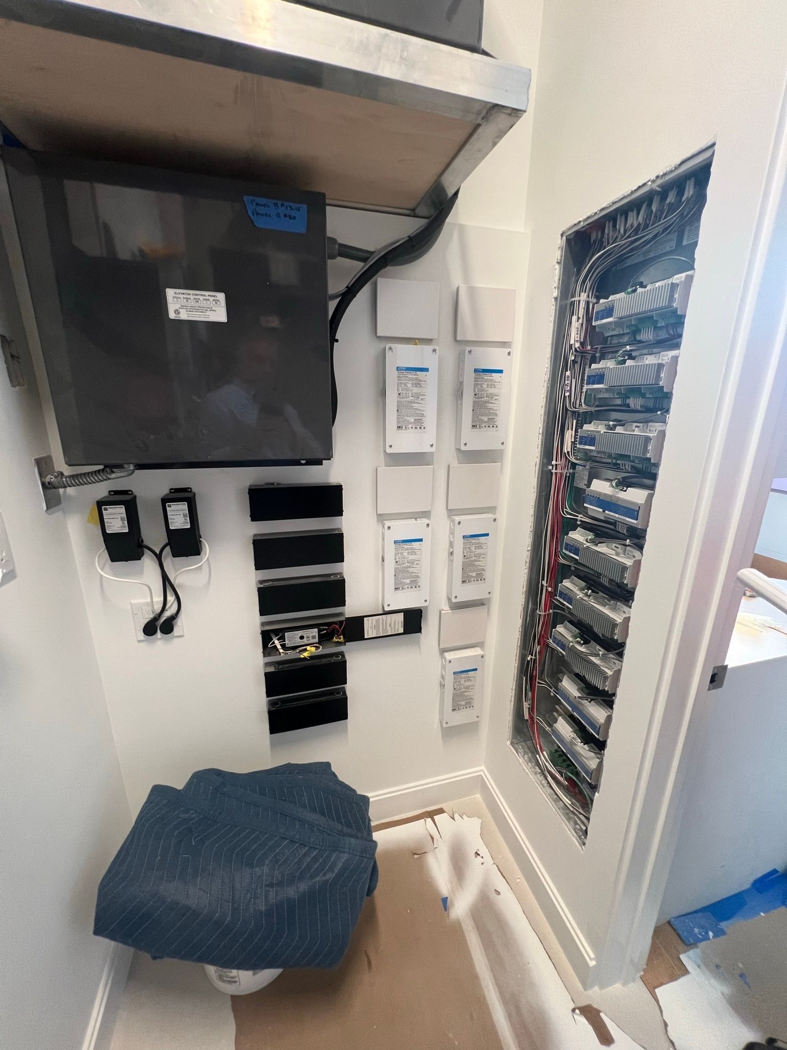 Electrical panel and components installed in a small, white utility closet.