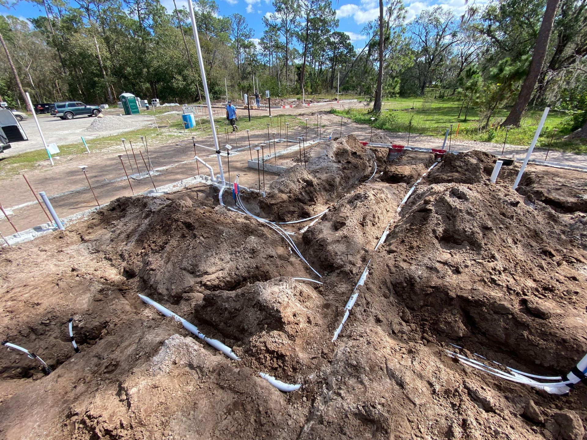 Dirt mound with white pipes laid out, construction site.