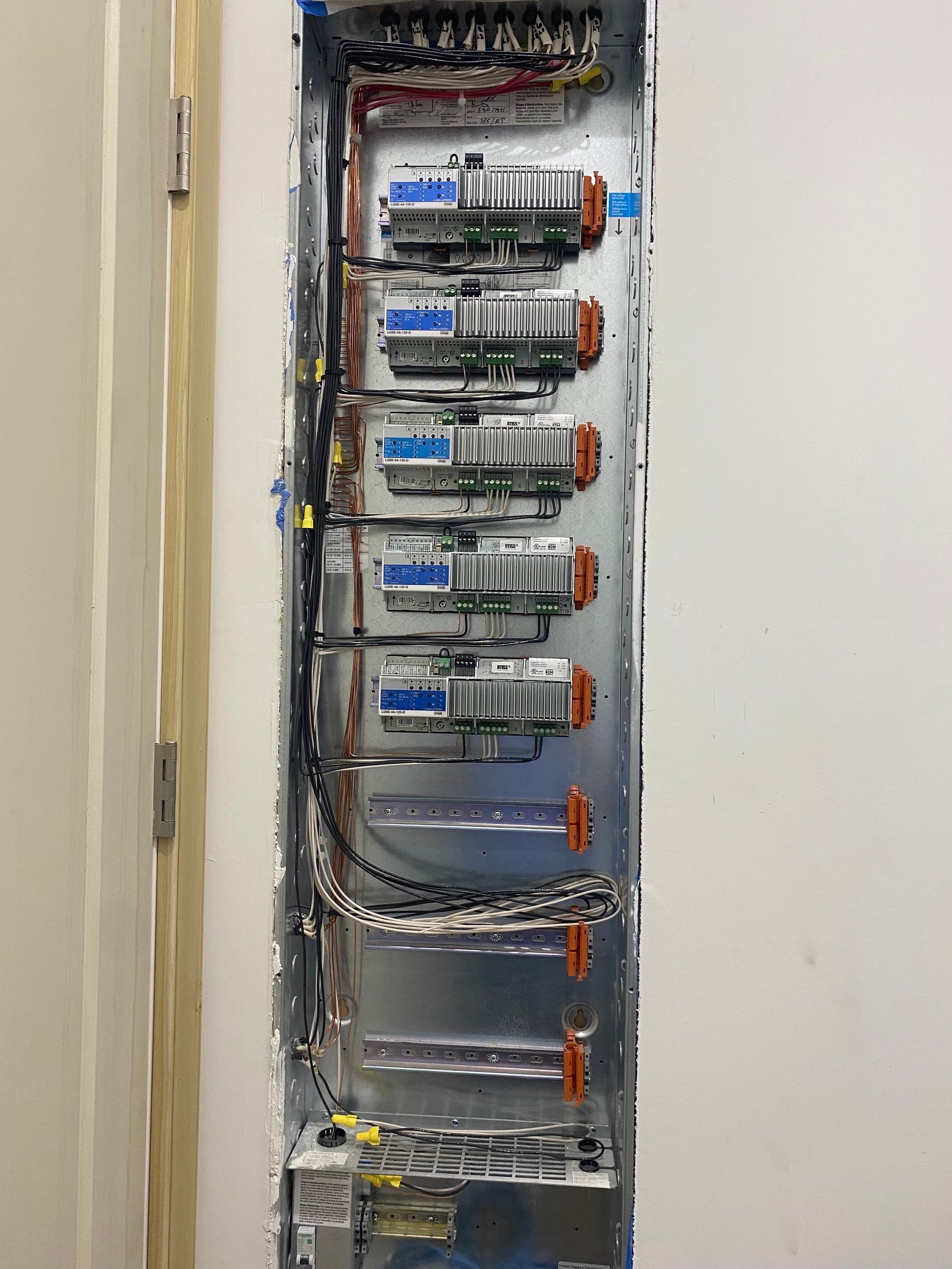 Electrical panel with circuit breakers and wiring installed inside a wall.