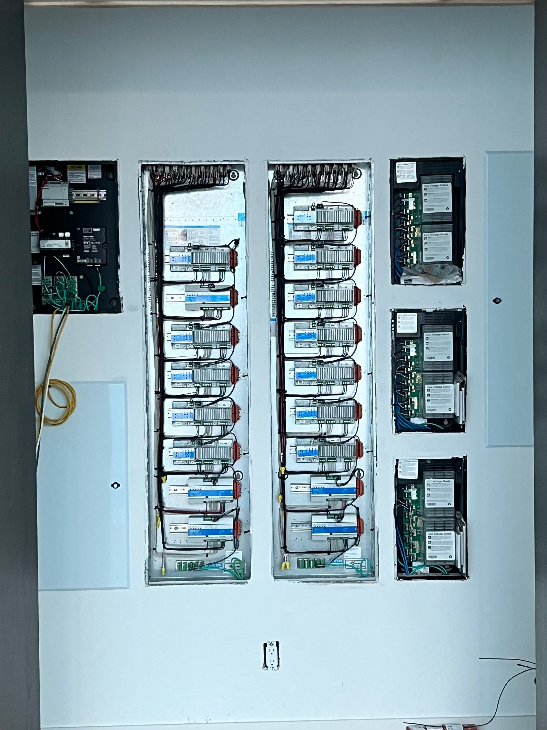 Electrical panel with open circuit breakers installed on a white wall.