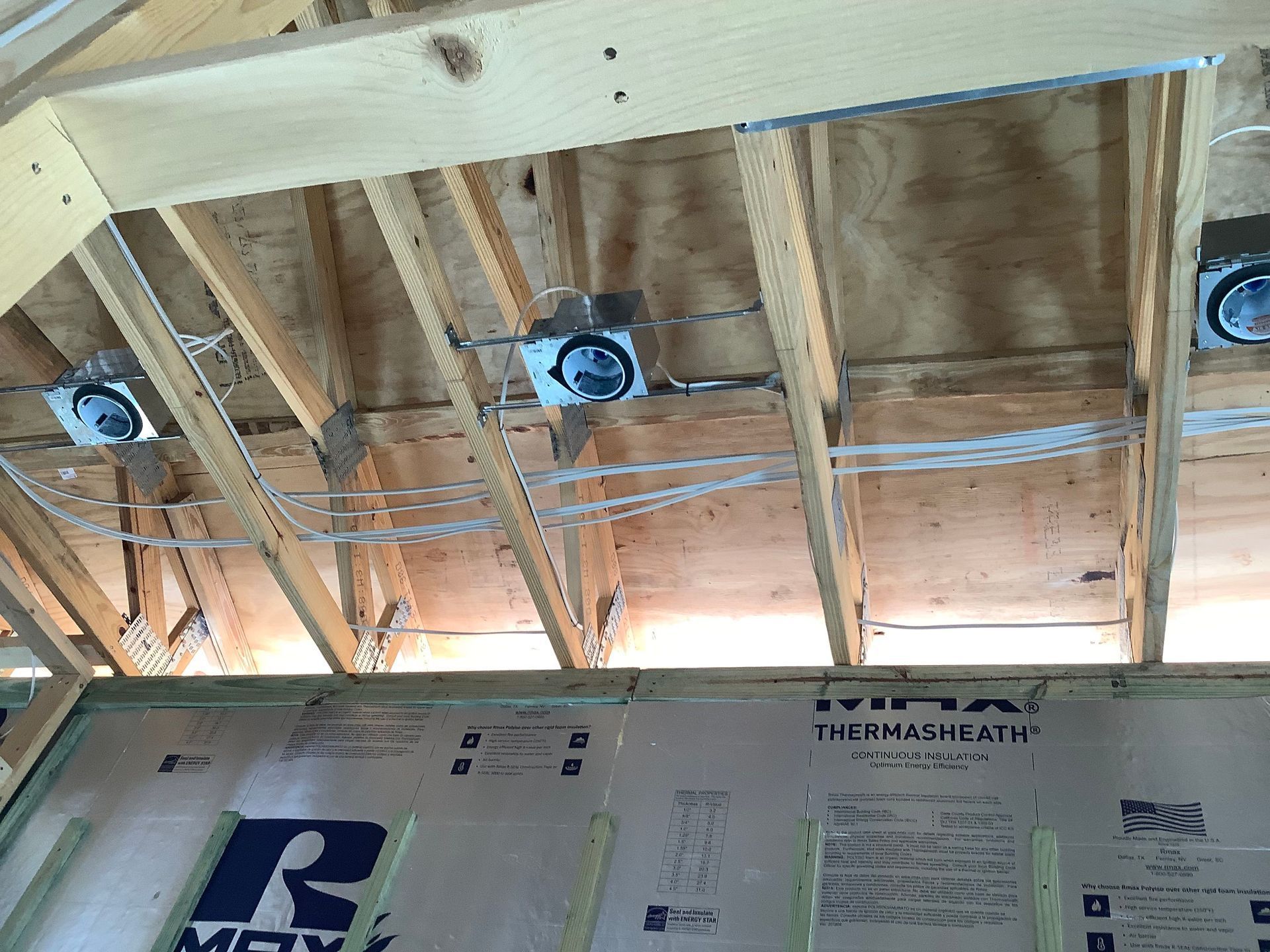 Wooden ceiling framework with recessed lights, electrical wiring, and insulation.