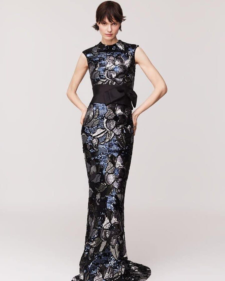 A woman is wearing a long black dress with a floral pattern