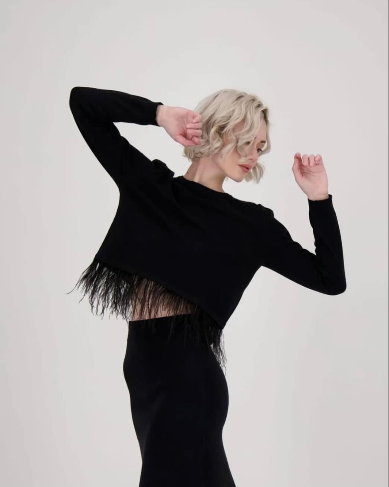 A woman is wearing a black top with feathers on the back