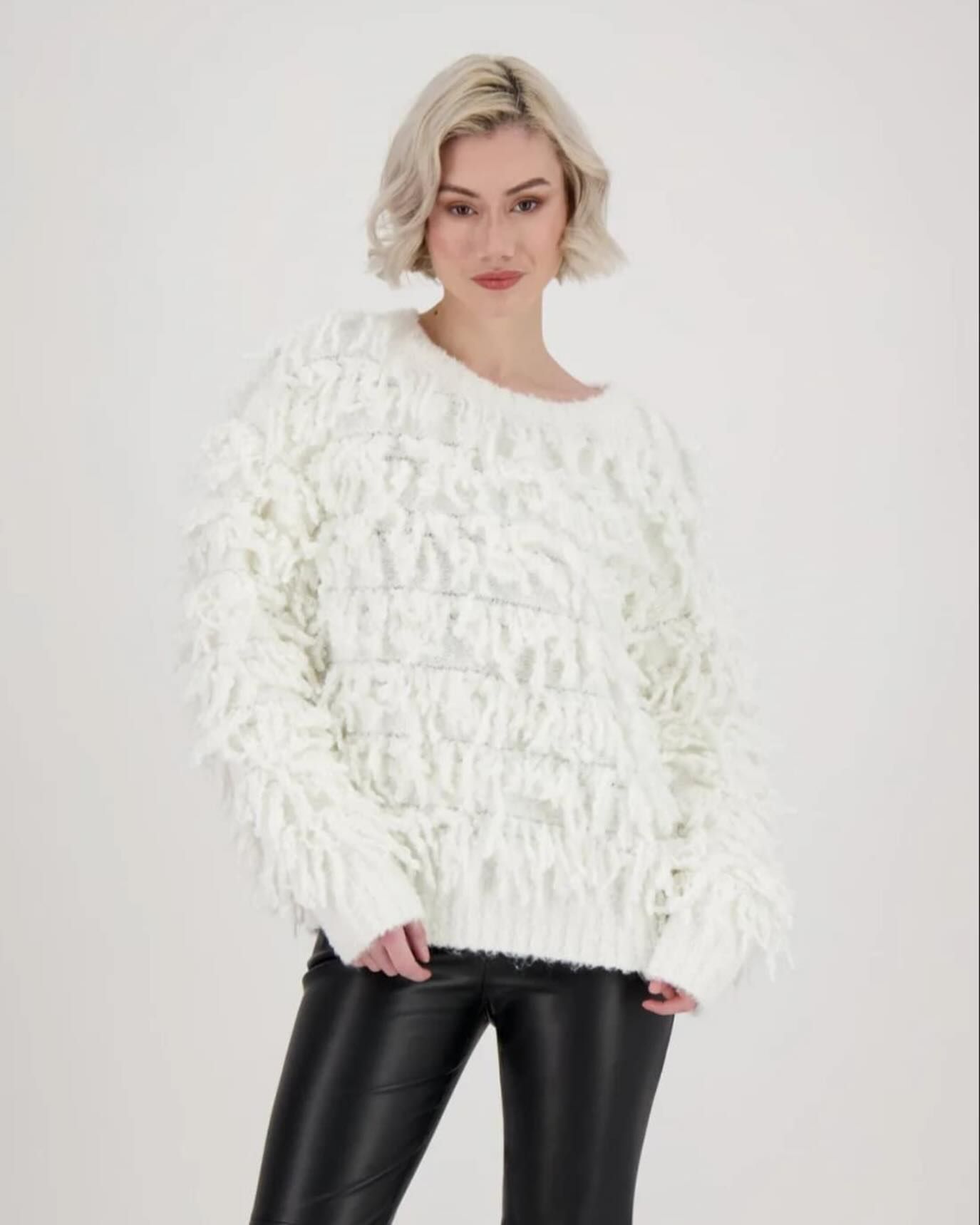 A woman wearing a white sweater and black pants