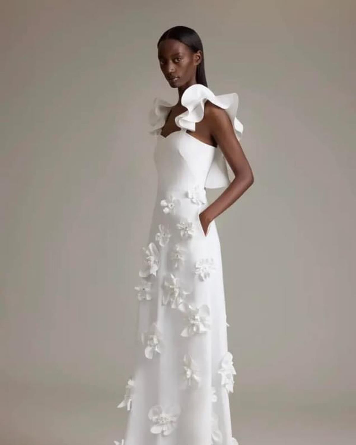 A woman is wearing a white dress with a bow on the shoulder.
