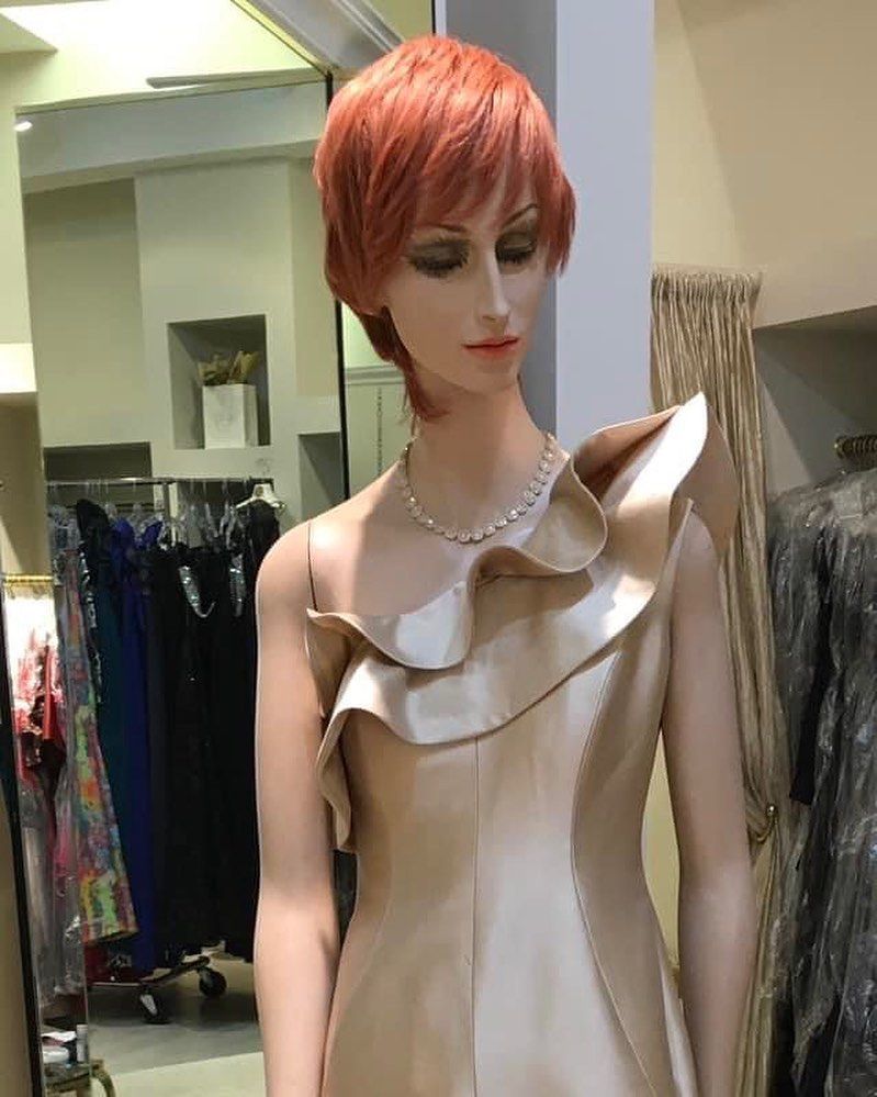A mannequin with red hair is wearing a dress and a necklace.