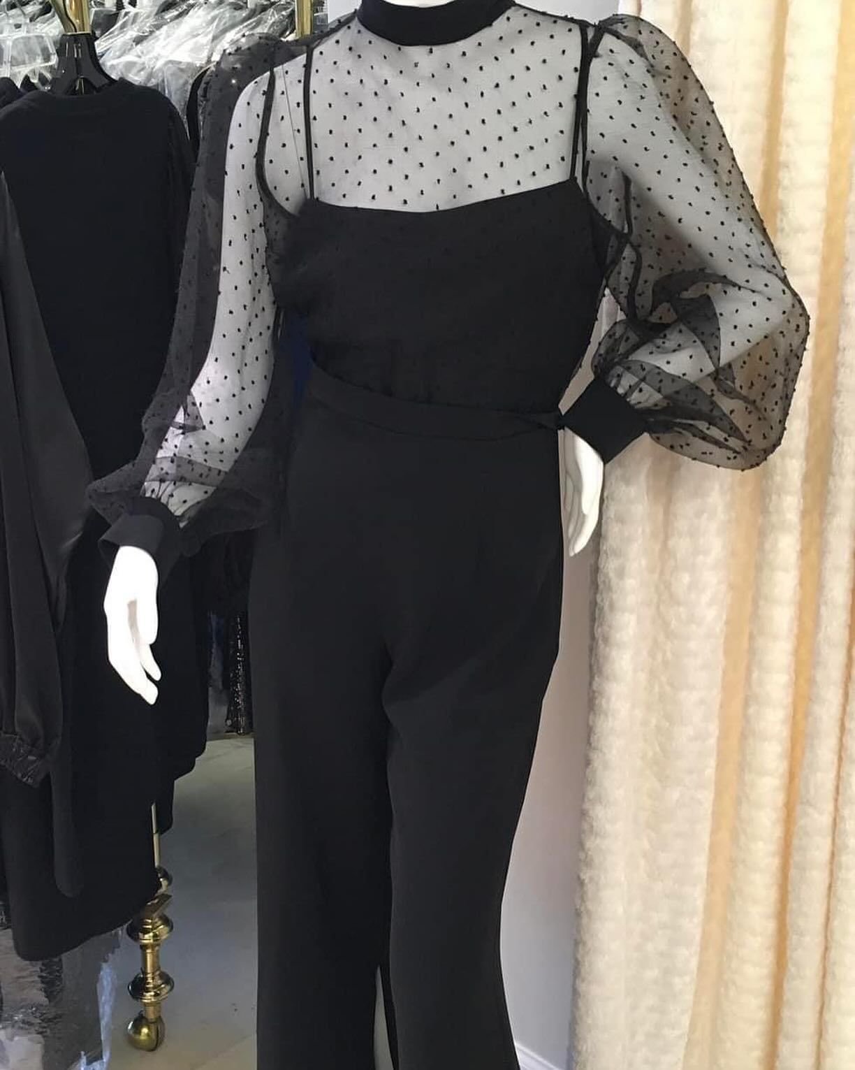 A mannequin wearing a black jumpsuit with polka dot sleeves