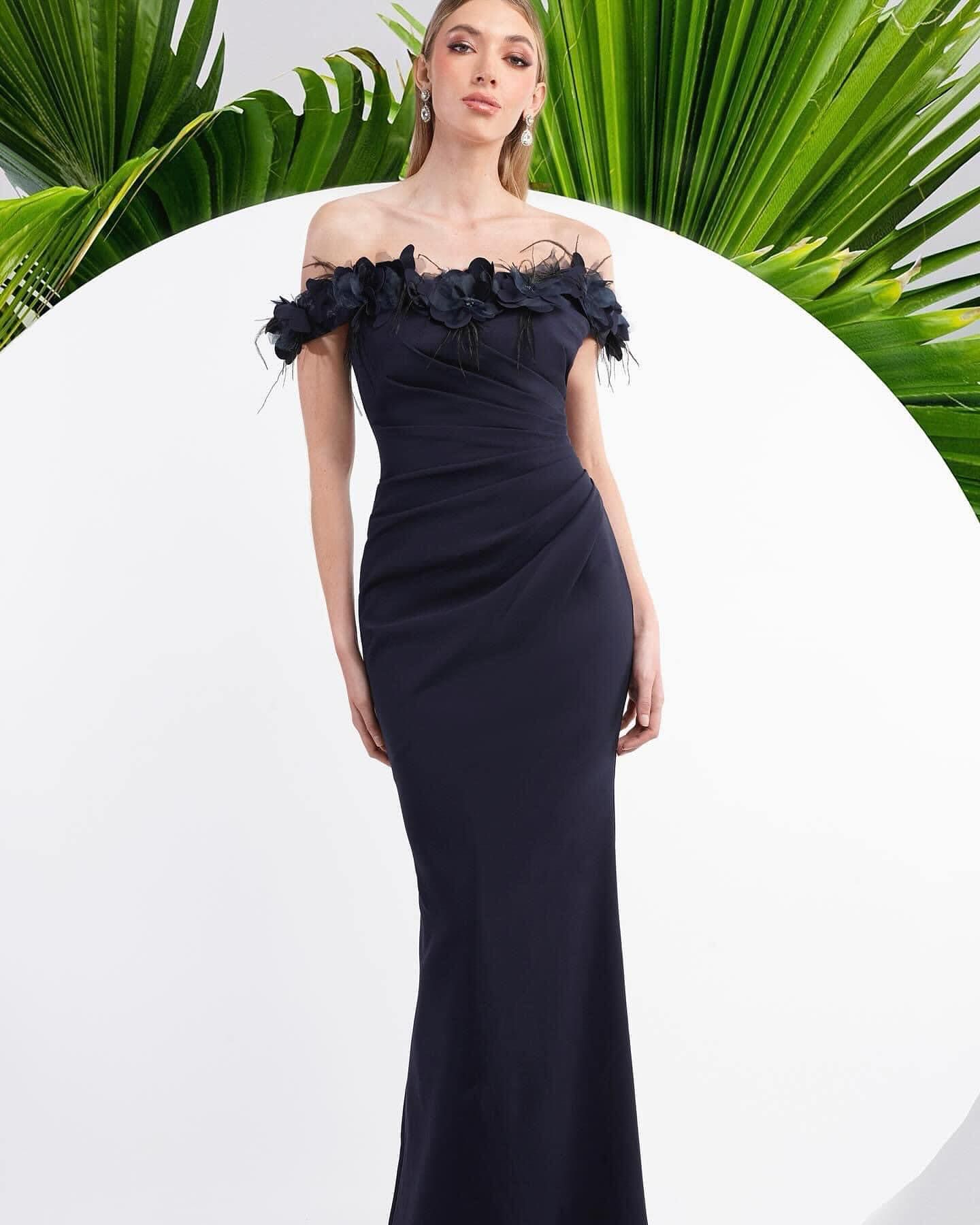 A woman is wearing a black off the shoulder dress.