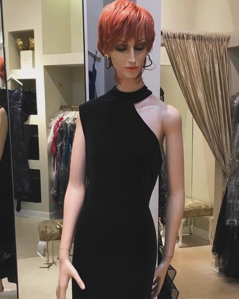 A mannequin with red hair is wearing a black dress