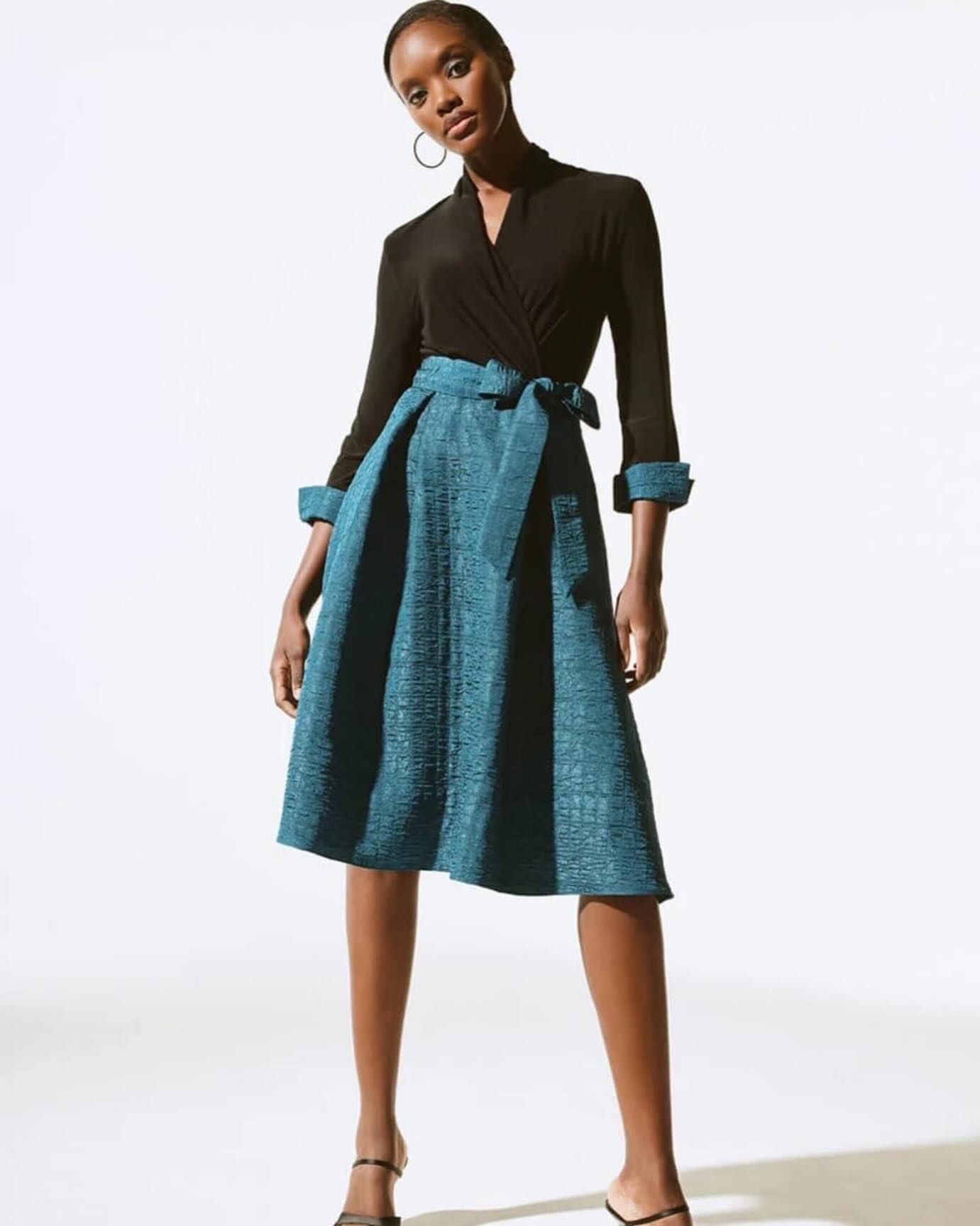 A woman is wearing a black top and a blue skirt.