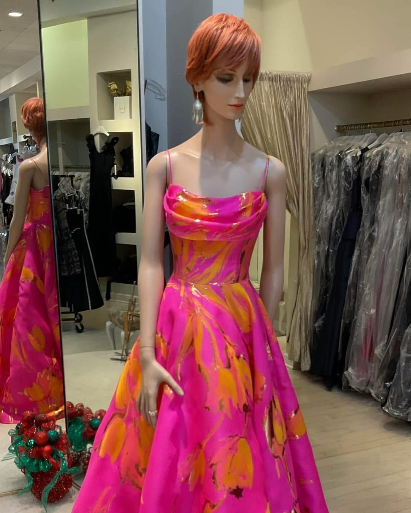 A mannequin is wearing a bright pink and orange dress