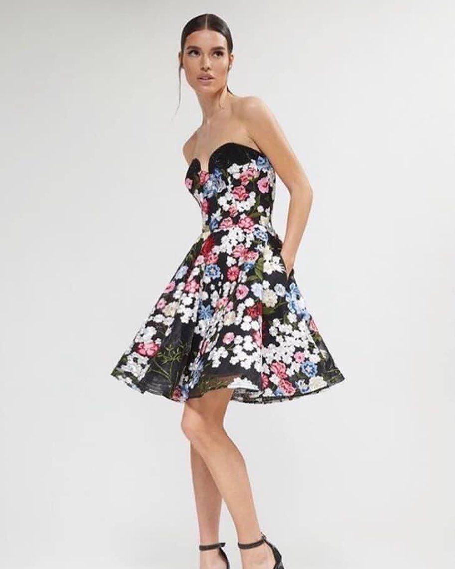 A woman is wearing a strapless dress with a floral print