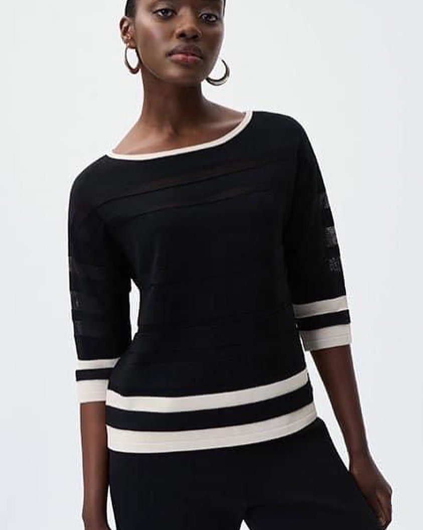 A woman is wearing a black sweater with white stripes on the sleeves.