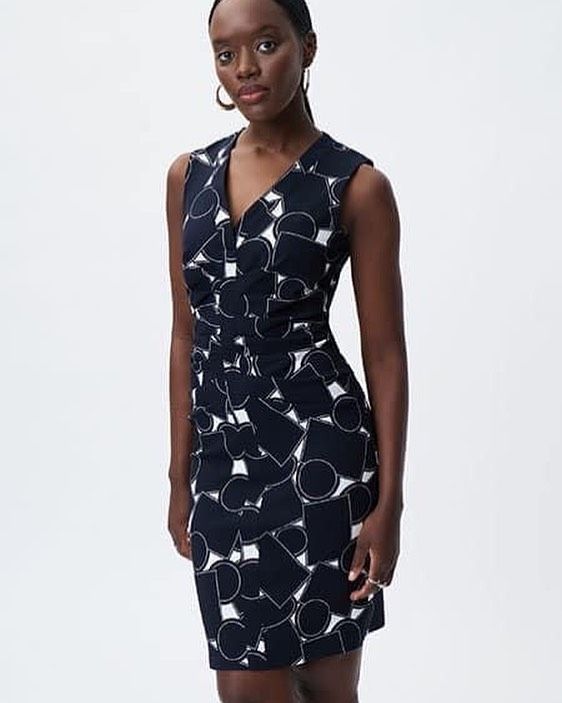 A woman is wearing a black dress with white circles on it.