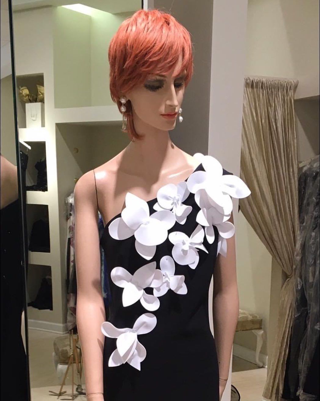 A mannequin with red hair is wearing a black dress with white flowers on it