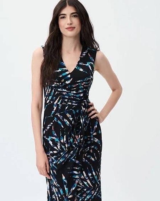 A woman in a black and blue dress is standing with her hands on her hips.