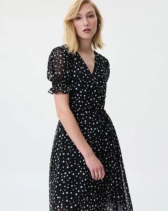 A woman is wearing a black dress with white polka dots.