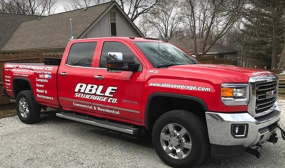 A red able security co truck is parked in front of a house