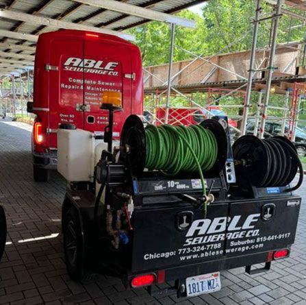 A able sewerage company truck is parked next to a trailer