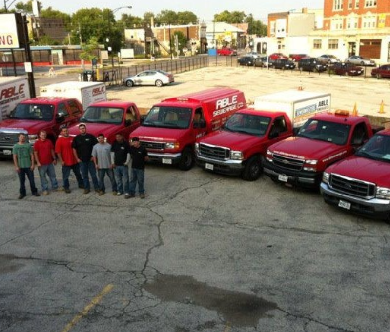 A group of men standing in front of a row of red fable trucks