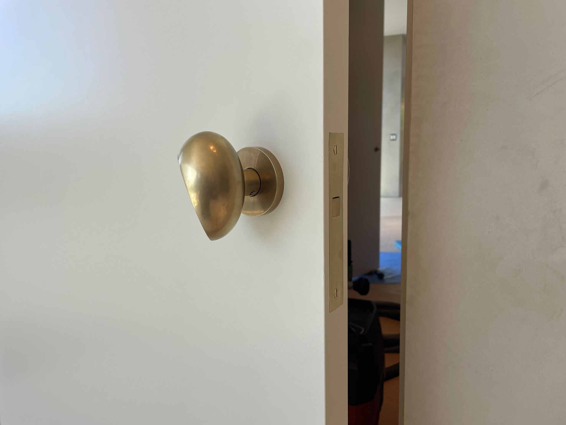 Brass doorknob on a white door, partially open to a room beyond.