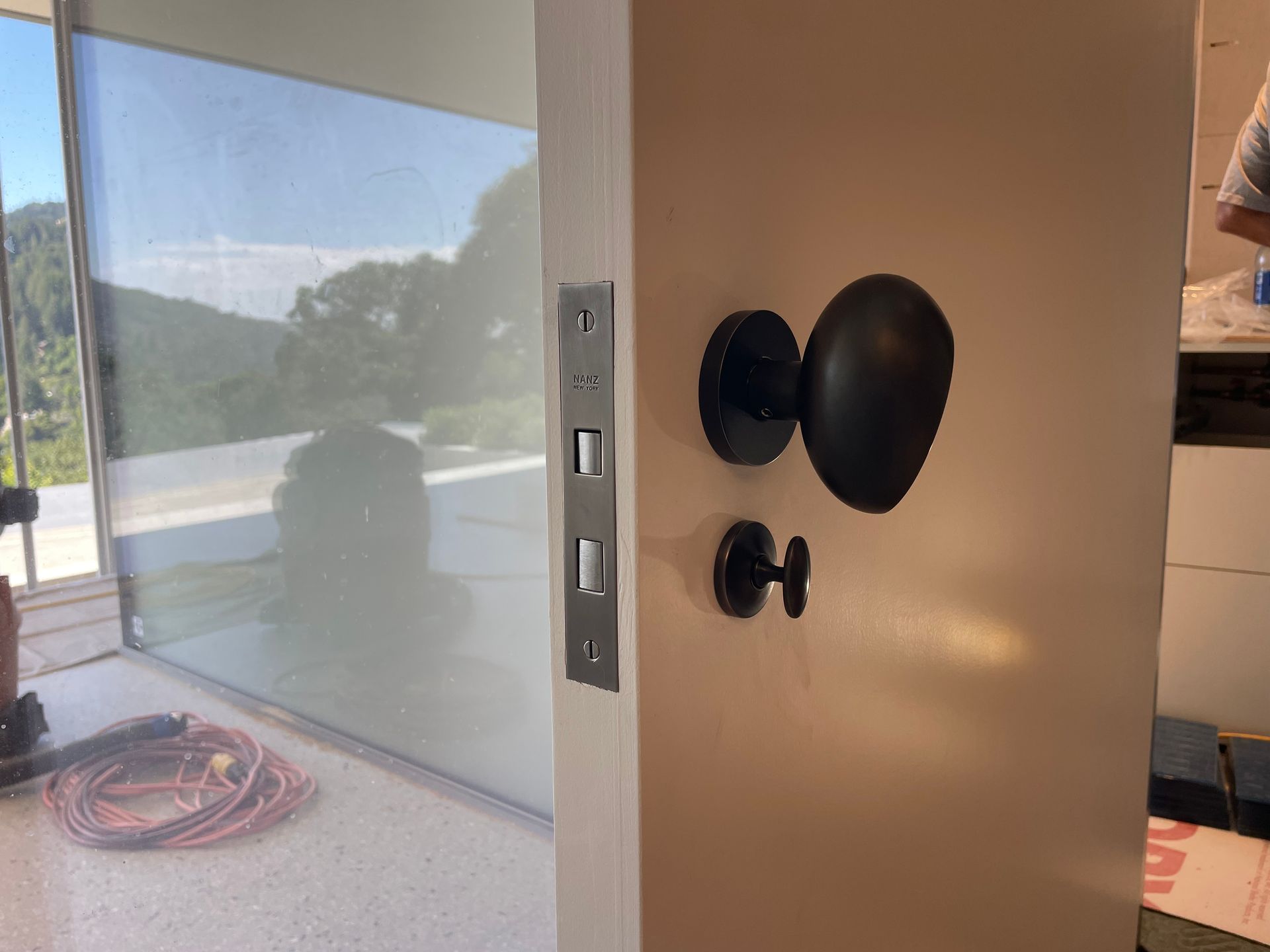 Open front door with black handle and bright patio view through glass panels.