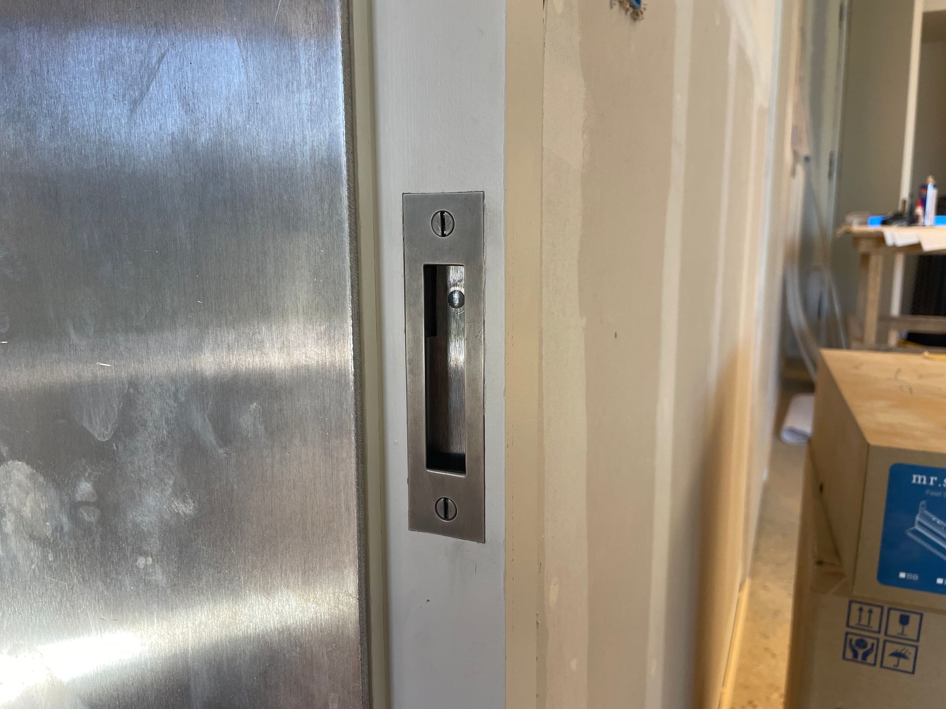 Close-up of a wall-mounted metal door handle beside a frosted glass door in a hallway