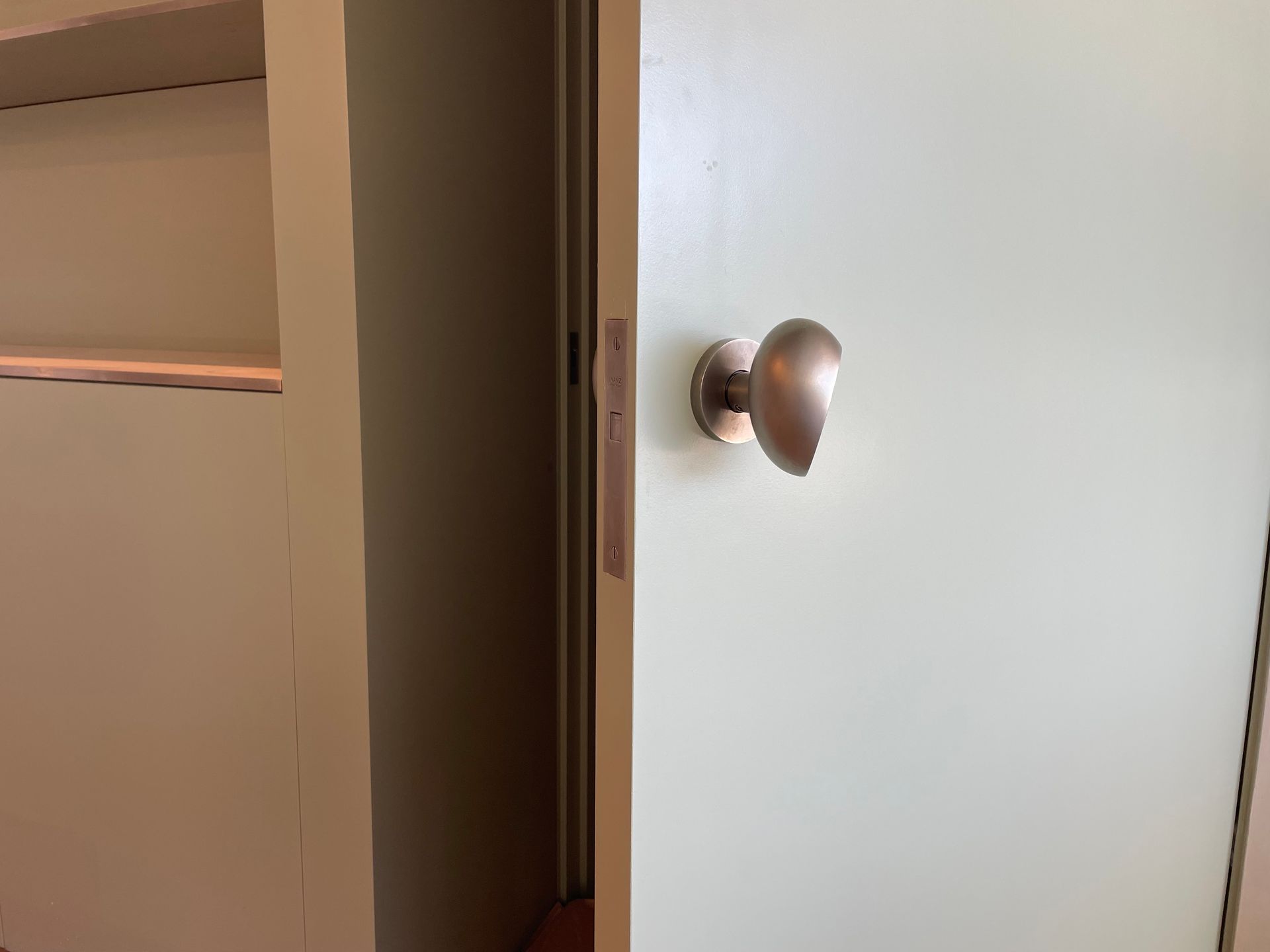 Partially open white door with a round silver knob, revealing a closet or hallway interior