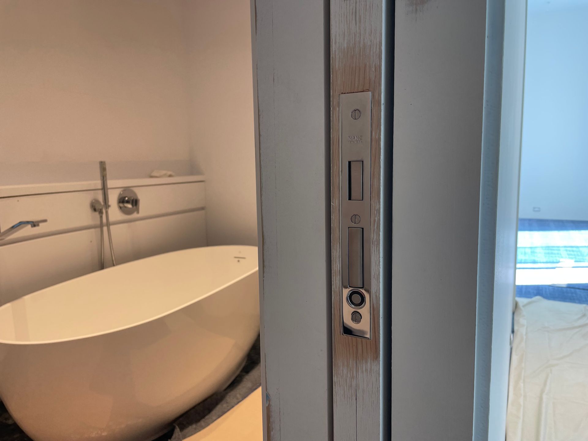 Modern bathroom with a freestanding white tub and a shower control panel in the foreground
