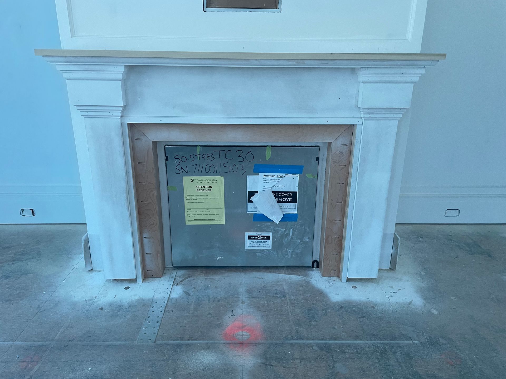 Fireplace with white mantle, metal interior, and scattered debris on concrete floor.