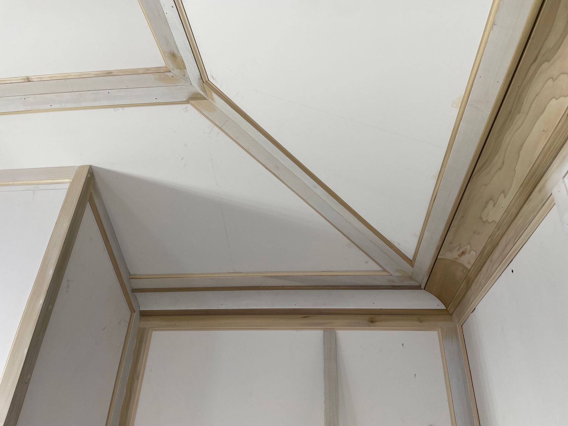 Interior corner of a room, white walls and ceiling with natural wood trim.