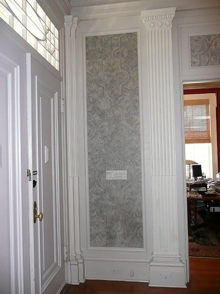 A hallway with white columns and a stained glass window