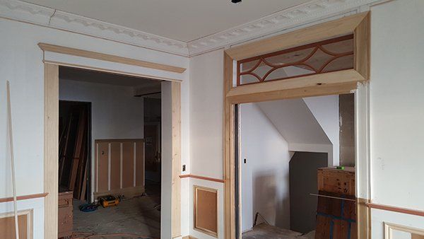 A room with a wooden door and a staircase in the background