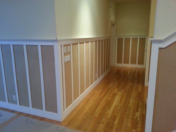 A hallway with wooden floors and paneling on the walls