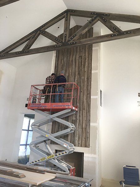 A man is standing on a scissor lift in a room